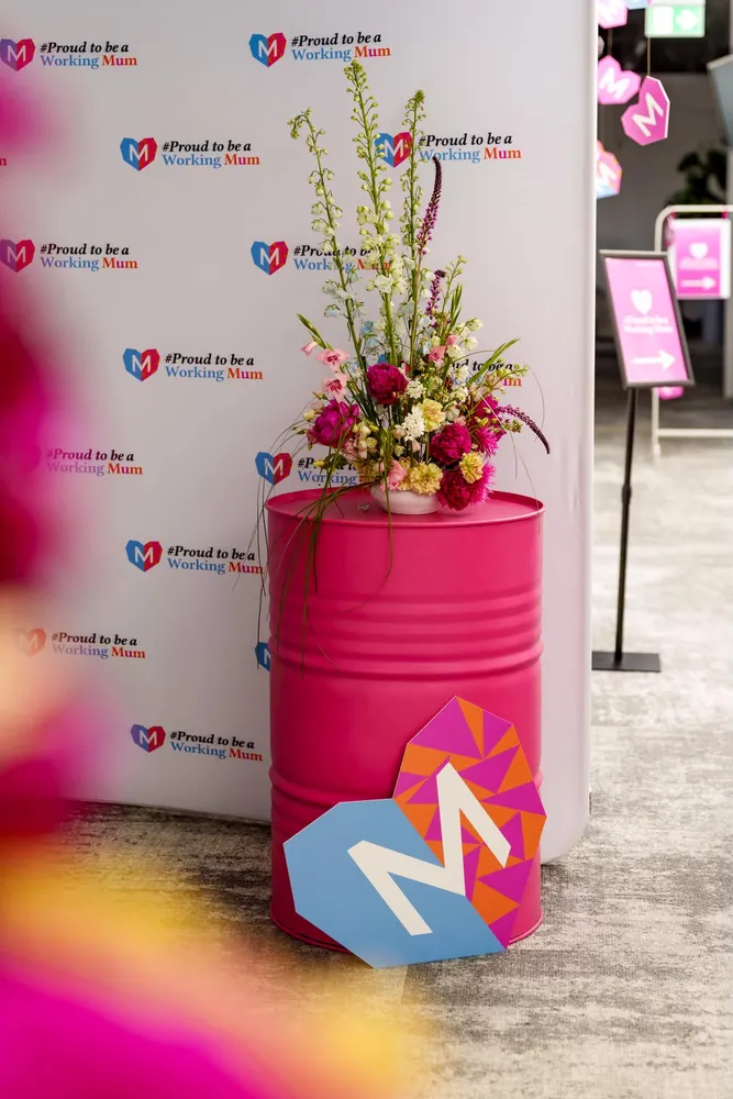 Wysoka kompozycja z ostróżką i piwoniami na różowej beczce przy ściance eventowej