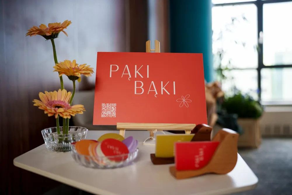 Stolik z tablicą Pąki Bąki, gerberami i wizytówkami